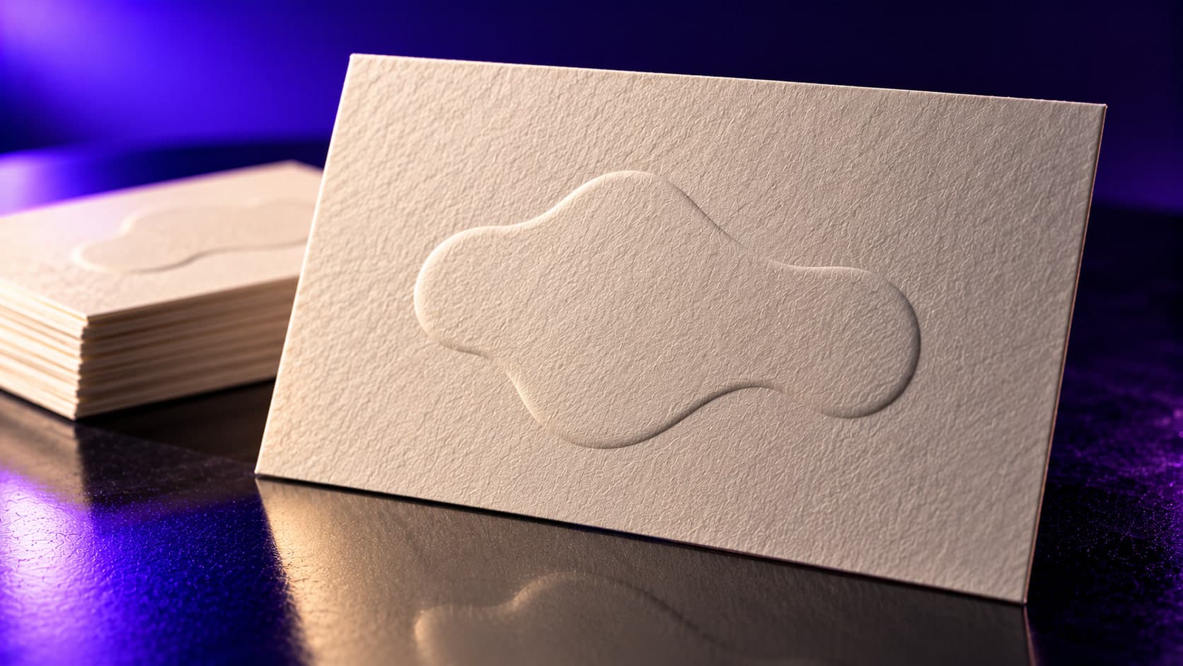 A cotton-stock business card with a blind-embossed mark in raking light